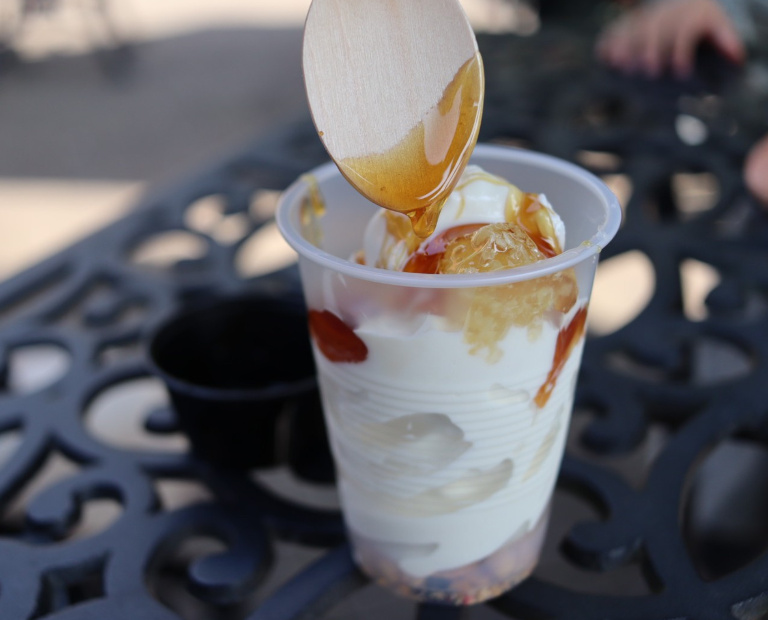 「ハニーデュウ」の「プレミアムコムハニーソフトクリーム」に蜂蜜をかけている写真